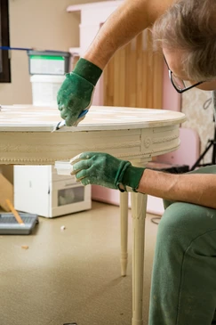 Vieille commode rénovée aux motifs sculptés turquoise située derrière un lit double dans une maison de campagne en bois, derrière un mur