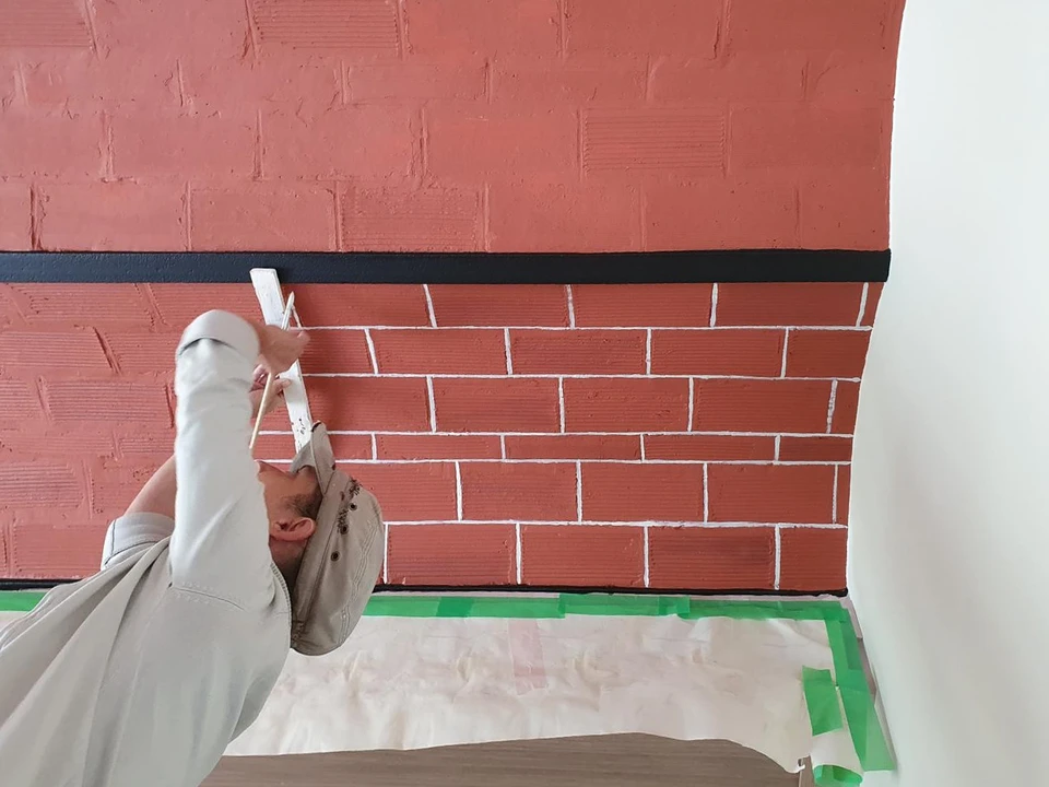 Famille de cinq personnes assise sur fond bleu clair, parents formant un toit protecteur avec leurs bras au-dessus de trois enfants souriants