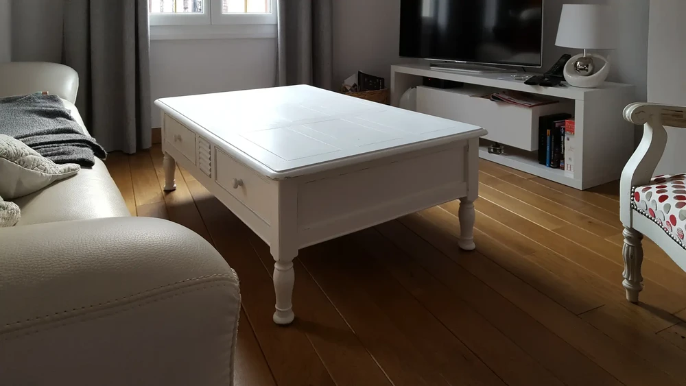 Décor intérieur maison dans les tons gris et marron : pot en verre avec fleurs séchées, vase et bougie sur le plateau en bois sur la table basse sur un canapé avec coussins