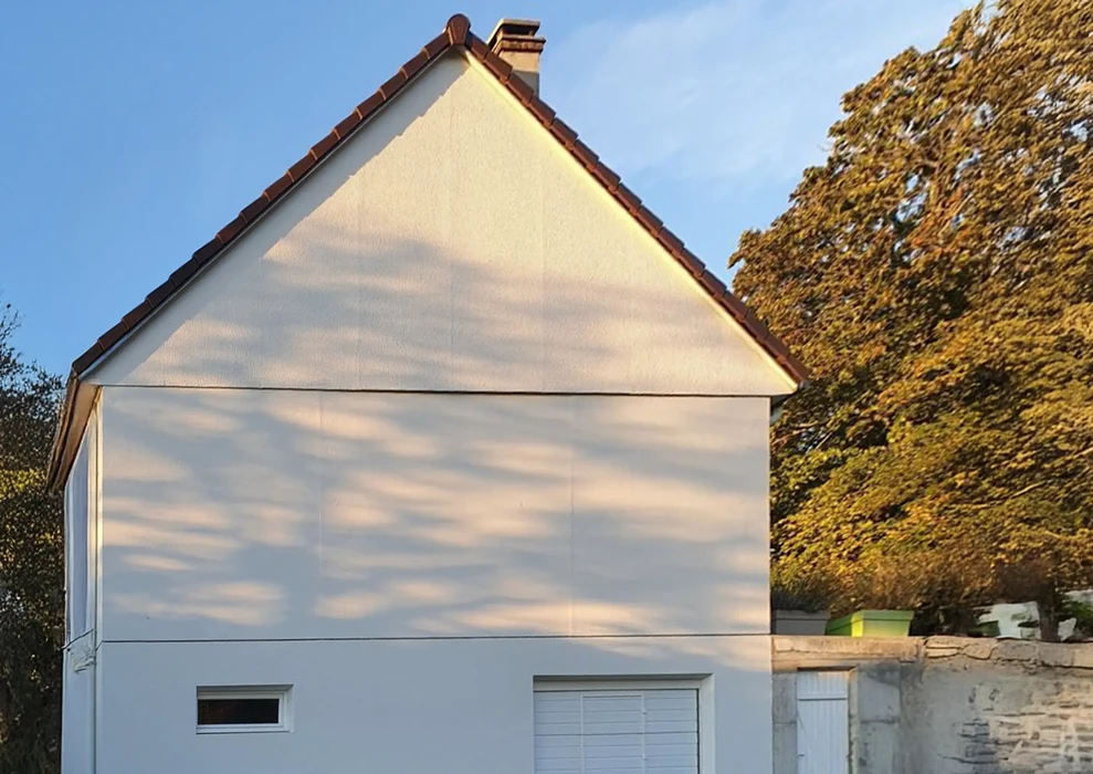 Maison contemporaine à trois niveaux avec façade blanche et accents de pierre naturelle sombre