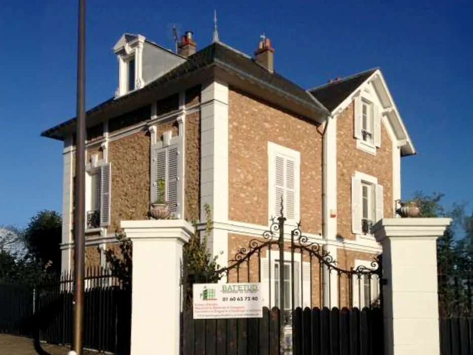 Chantier de rénovation extérieur montrant la restauration d'un mur en pierre
