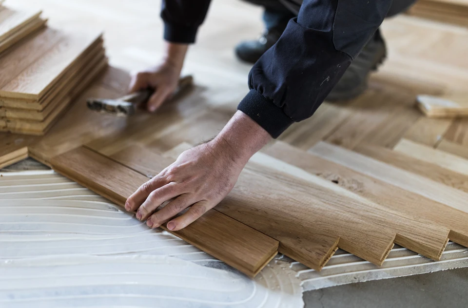 Menuisier mesurant et traçant des planches de bois avec une équerre et un crayon dans un atelier